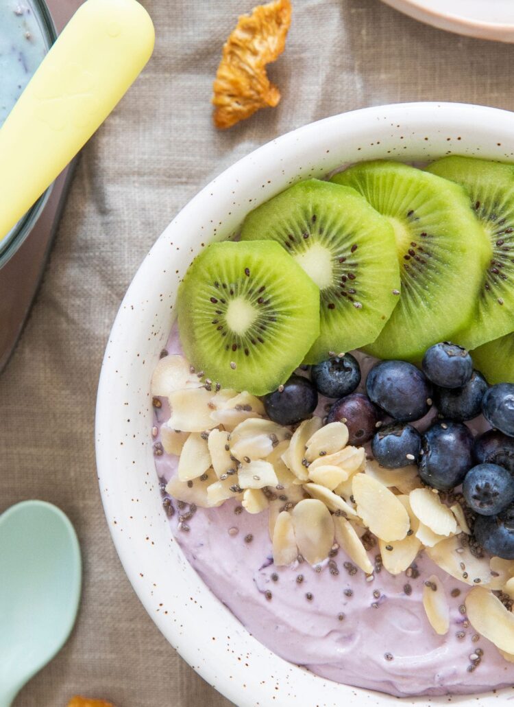 A bowl of yogurt topped with blueberries, kiwi, and granola. Perfect for your wellness journey!