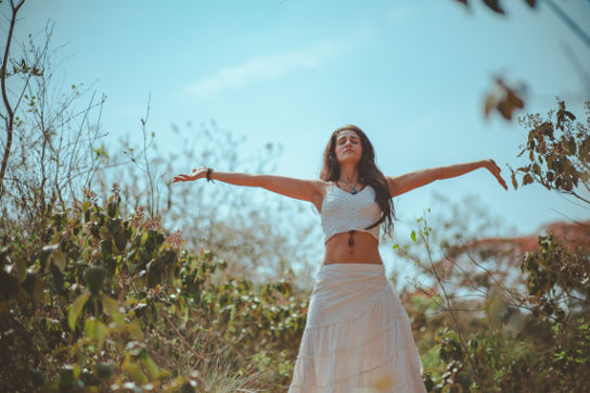 A woman in a white dress standing in a field, embracing her wellness journey.