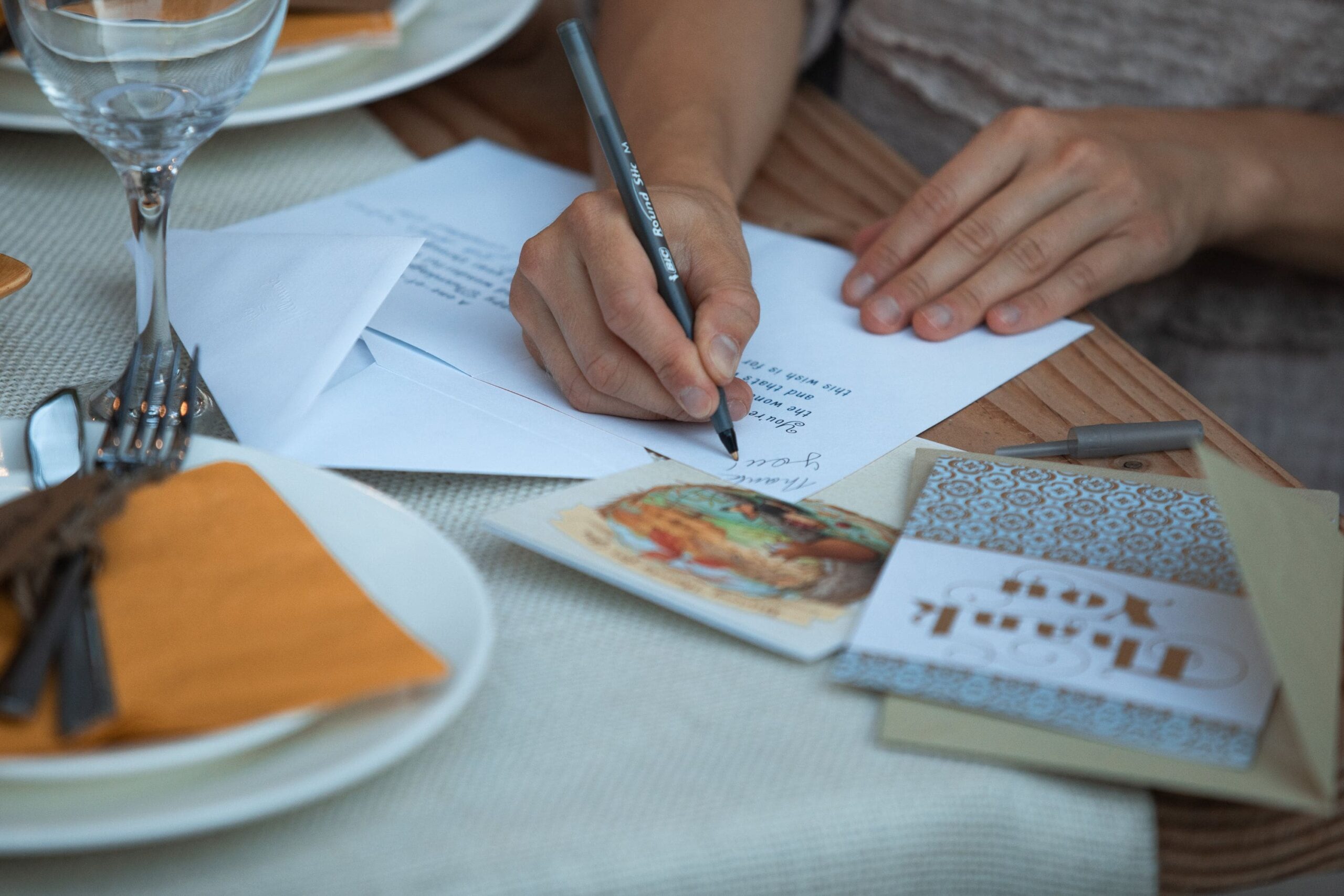 An individual using a gratitude journal prompts printable to write a thank you note on a table.