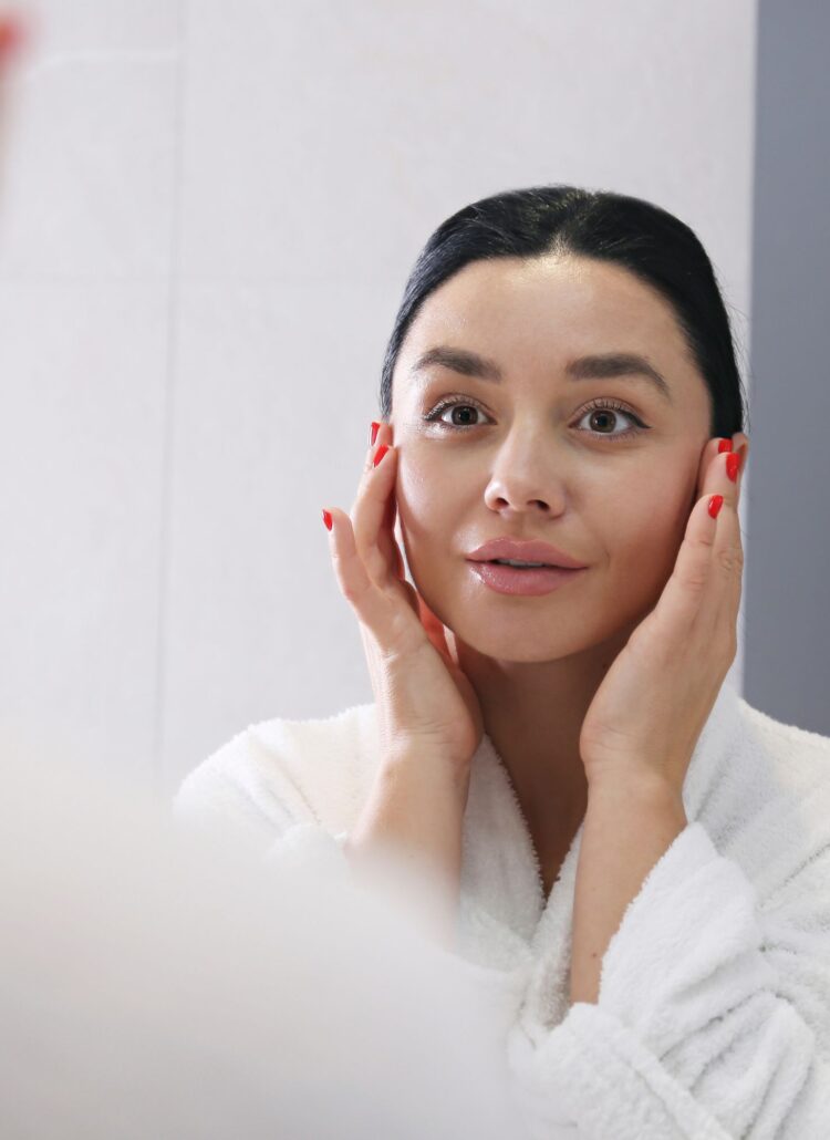 A woman applying makeup in front of a mirror as part of her morning self-care routine.